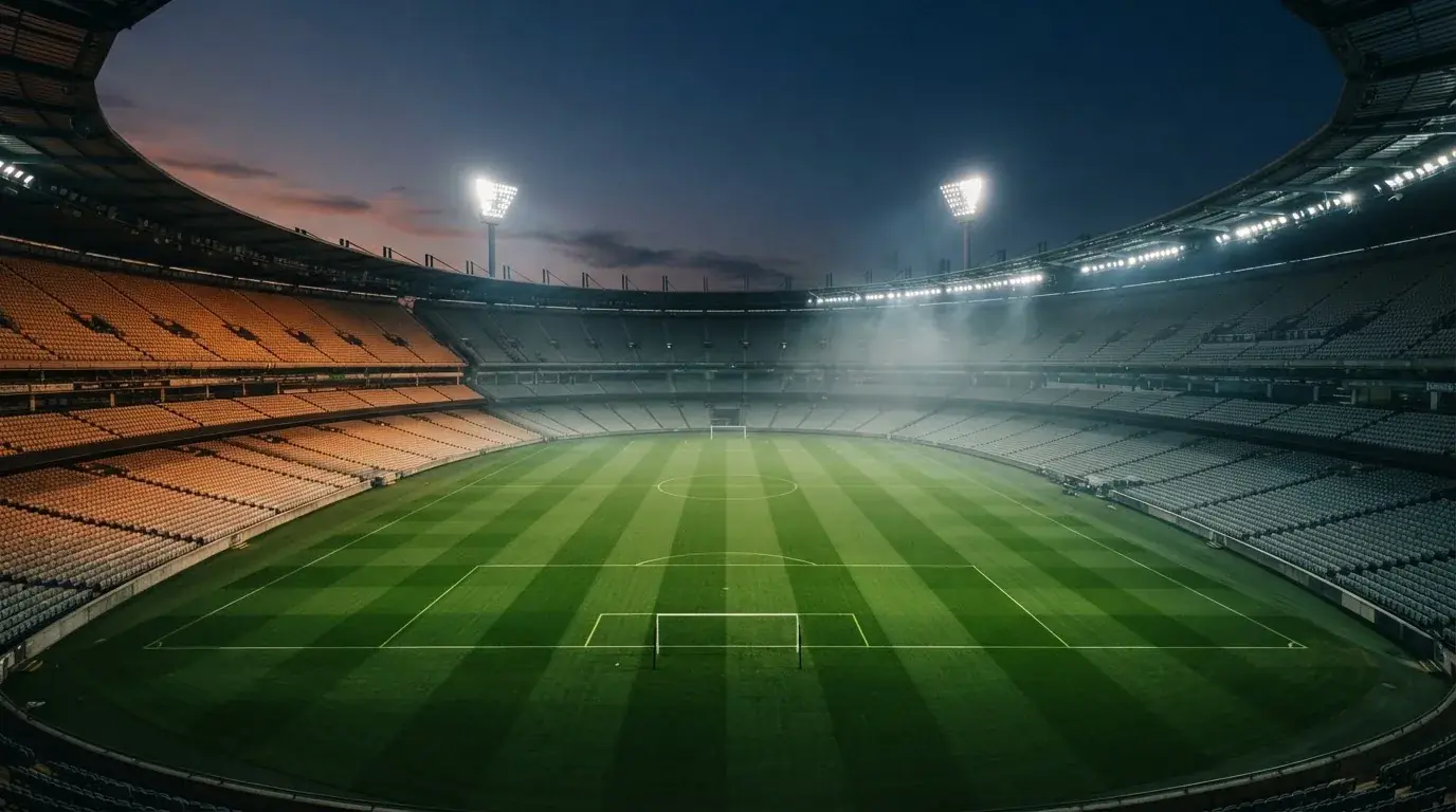 Een leeg voetbalstadion met lichtmasten bij schemering