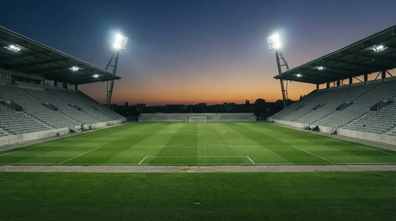 Een leeg voetbalstadion met lichtmasten bij schemering