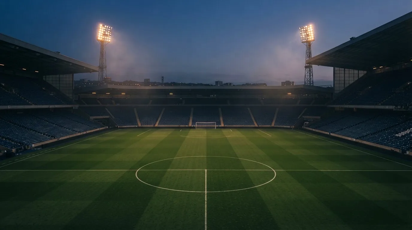 Een leeg voetbalstadion met lichtmasten bij schemering