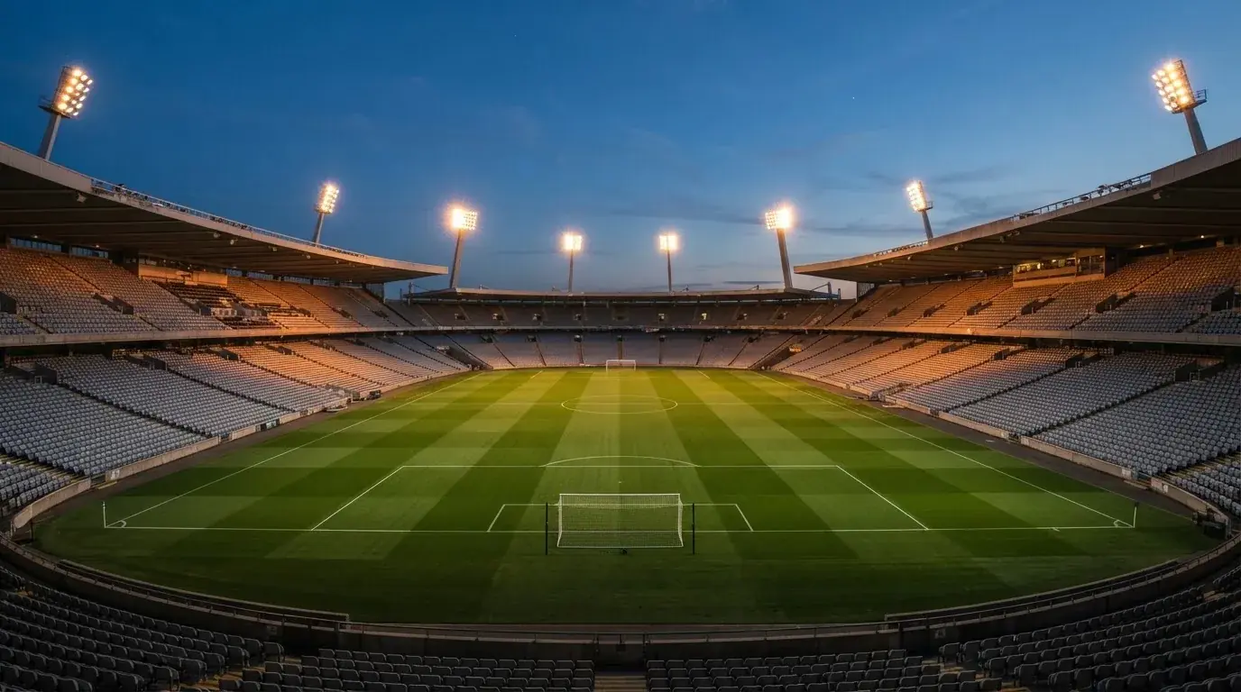 Een leeg voetbalstadion met lichtmasten bij schemering