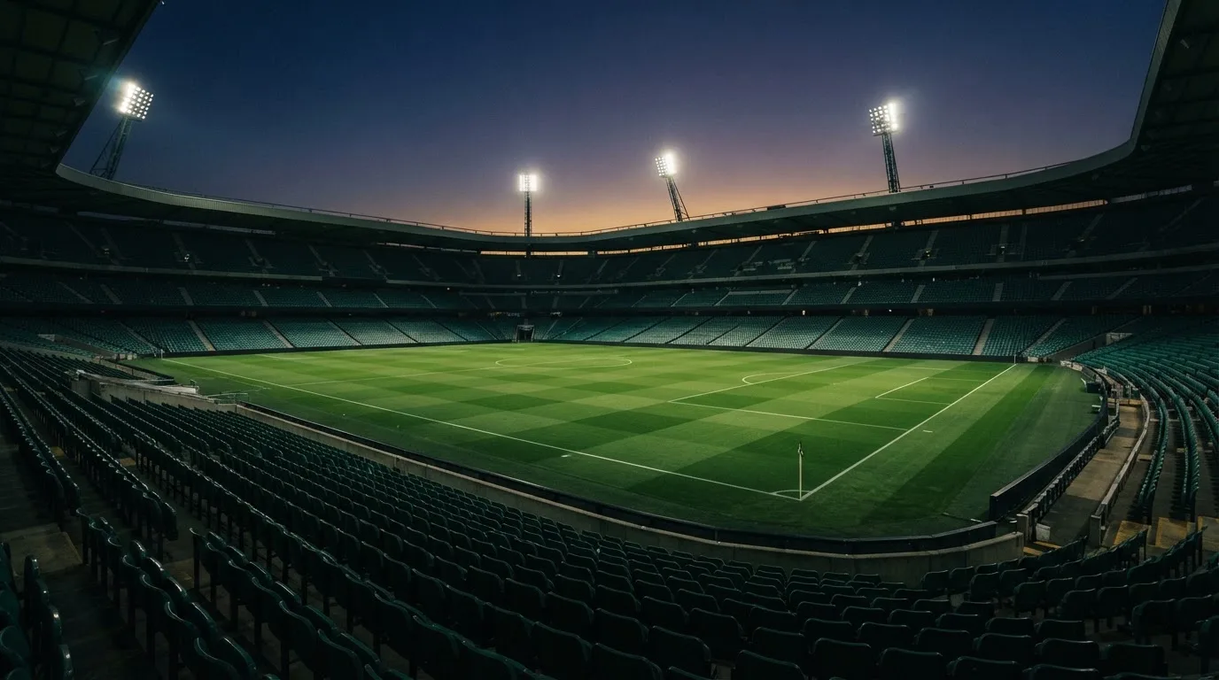Een leeg voetbalstadion met lichtmasten bij schemering