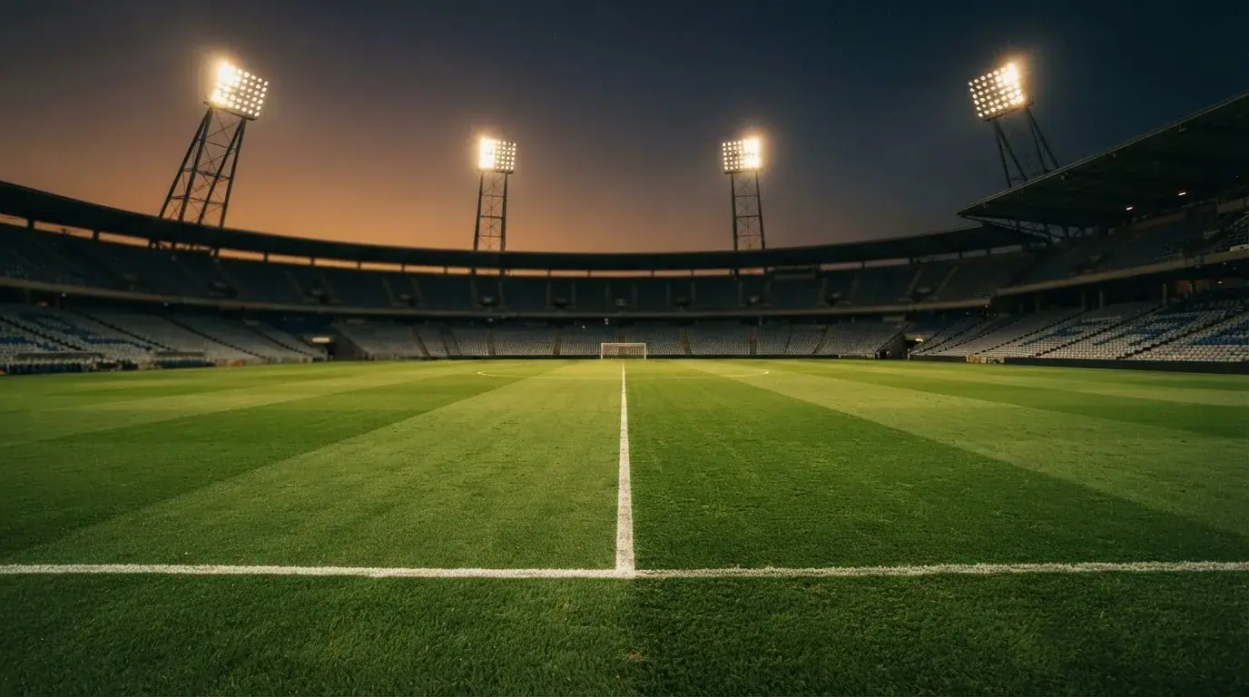 Een leeg voetbalstadion met lichtmasten bij schemering