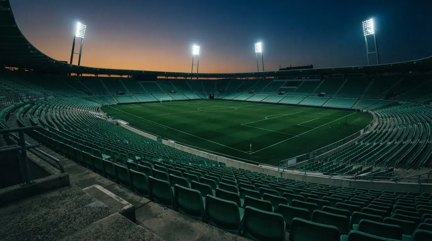 Een leeg voetbalstadion met lichtmasten bij schemering