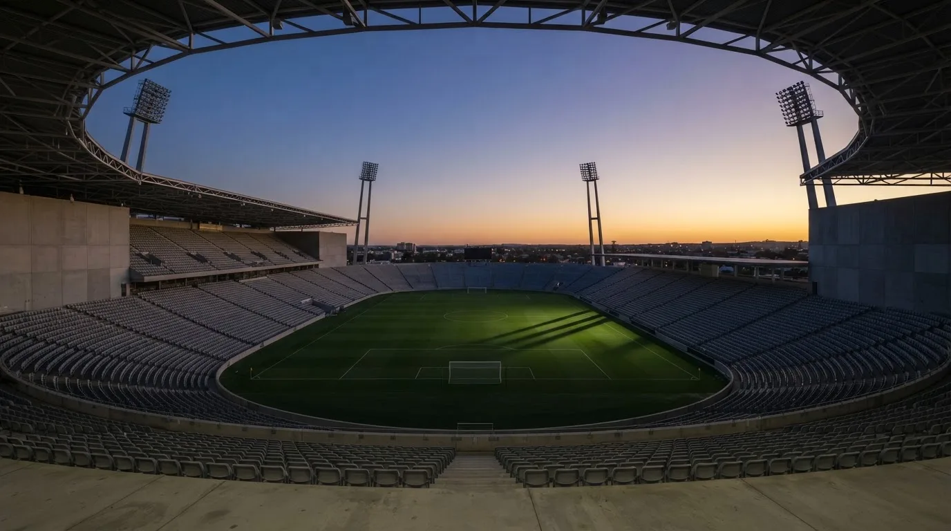 Een leeg voetbalstadion met lichtmasten bij schemering