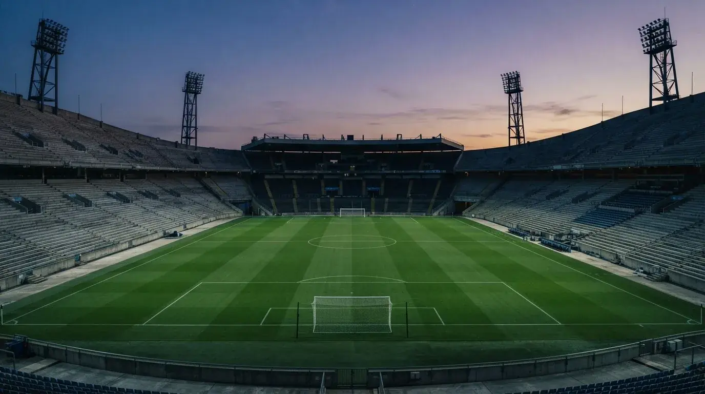 Een leeg voetbalstadion met lichtmasten bij schemering