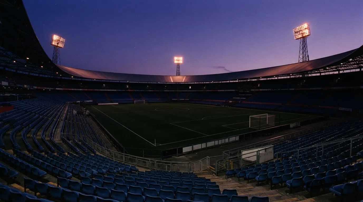 Een leeg voetbalstadion met lichtmasten bij schemering