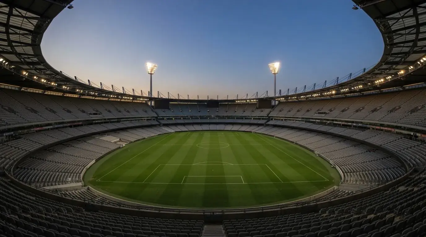 Een leeg voetbalstadion met lichtmasten bij schemering