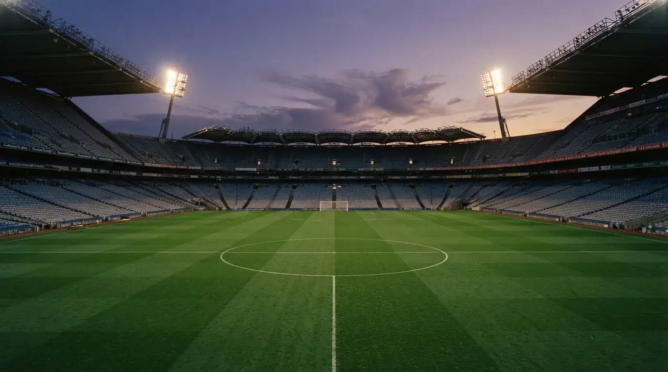 Een leeg voetbalstadion met lichtmasten bij schemering