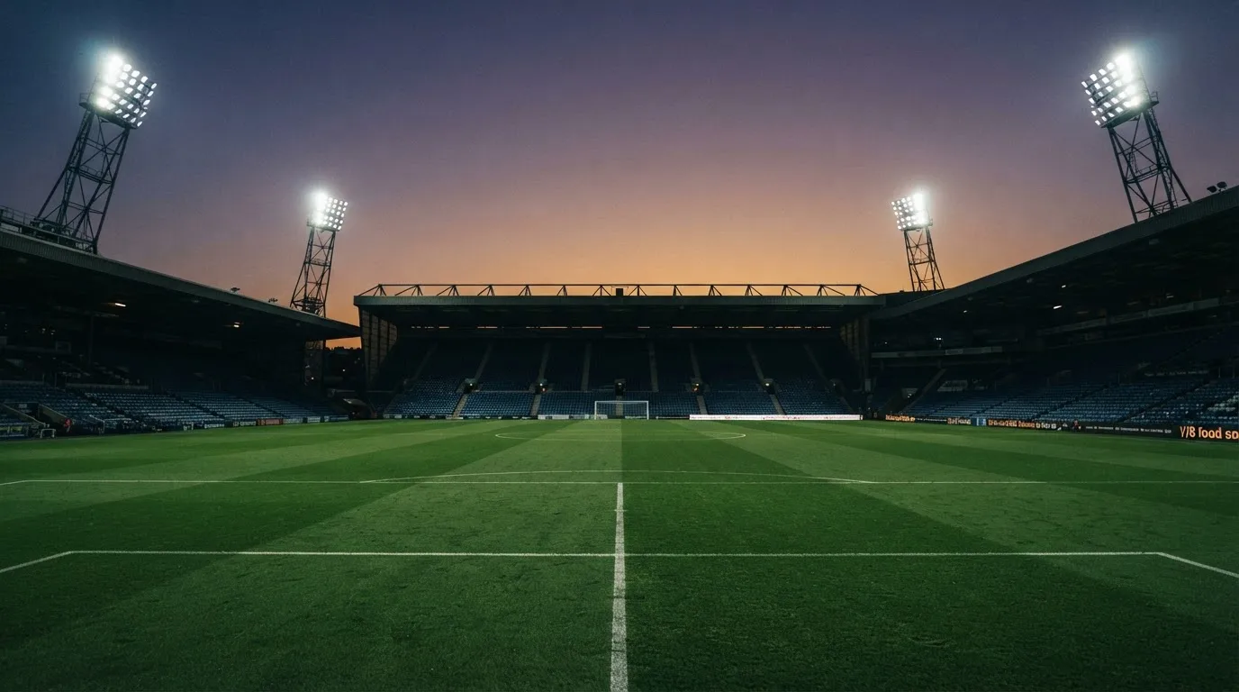 Een leeg voetbalstadion met lichtmasten bij schemering